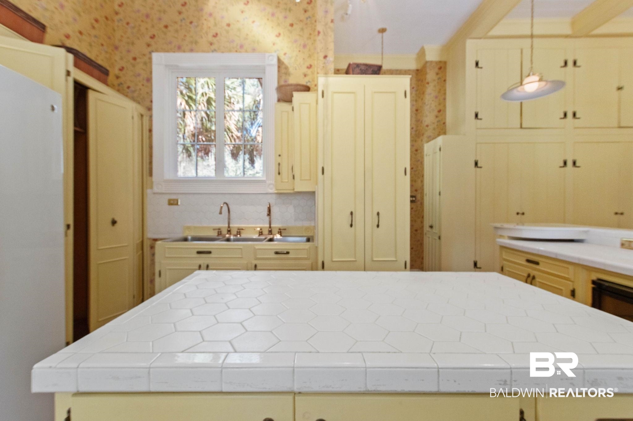 1701 Sowell Road Brewton, AL 36426 - Photo 37 of 83 Kitchen with wallpapered walls, a kitchen island, cream cabinets, freestanding refrigerator, and decorative light fixtures