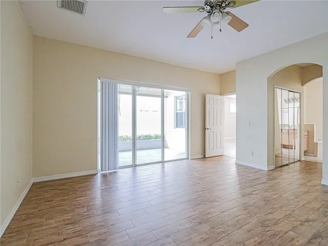 a view of an empty room with a window and wooden floor
