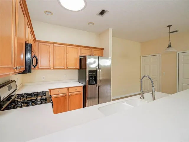 a kitchen with stainless steel appliances granite countertop a sink and a refrigerator