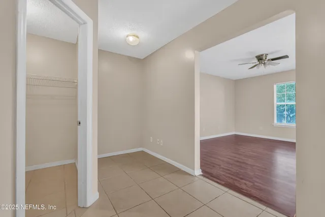 a view of an empty room with window and cabinet area