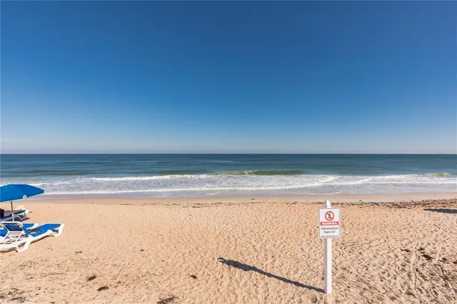 a view of a swimming pool with lawn chairs under an umbrella