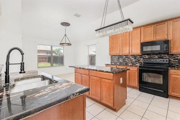 a kitchen with stainless steel appliances granite countertop a stove a sink and a microwave
