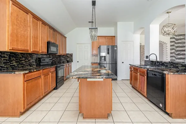 a kitchen with stainless steel appliances granite countertop a stove a sink and a refrigerator