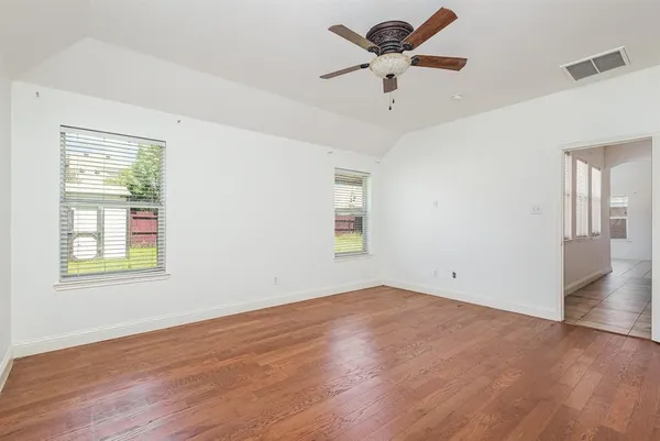 a view of a room with wooden floor and a ceiling fan