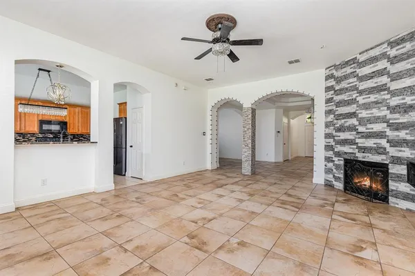 a view of a livingroom with a fireplace a chandelier fan and windows