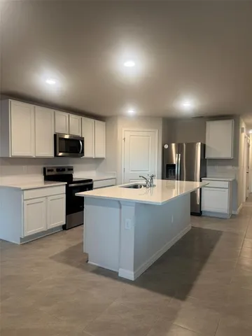 a large kitchen with a large counter top stainless steel appliances and cabinets