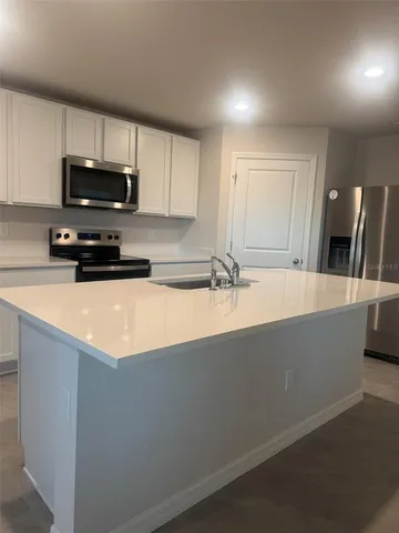 a kitchen with stainless steel appliances a sink a stove a microwave a refrigerator a counter top space and cabinets