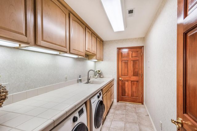 a utility room with a sink a cabinetry and appliances