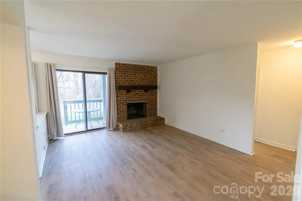 an empty room with wooden floor fireplace and windows