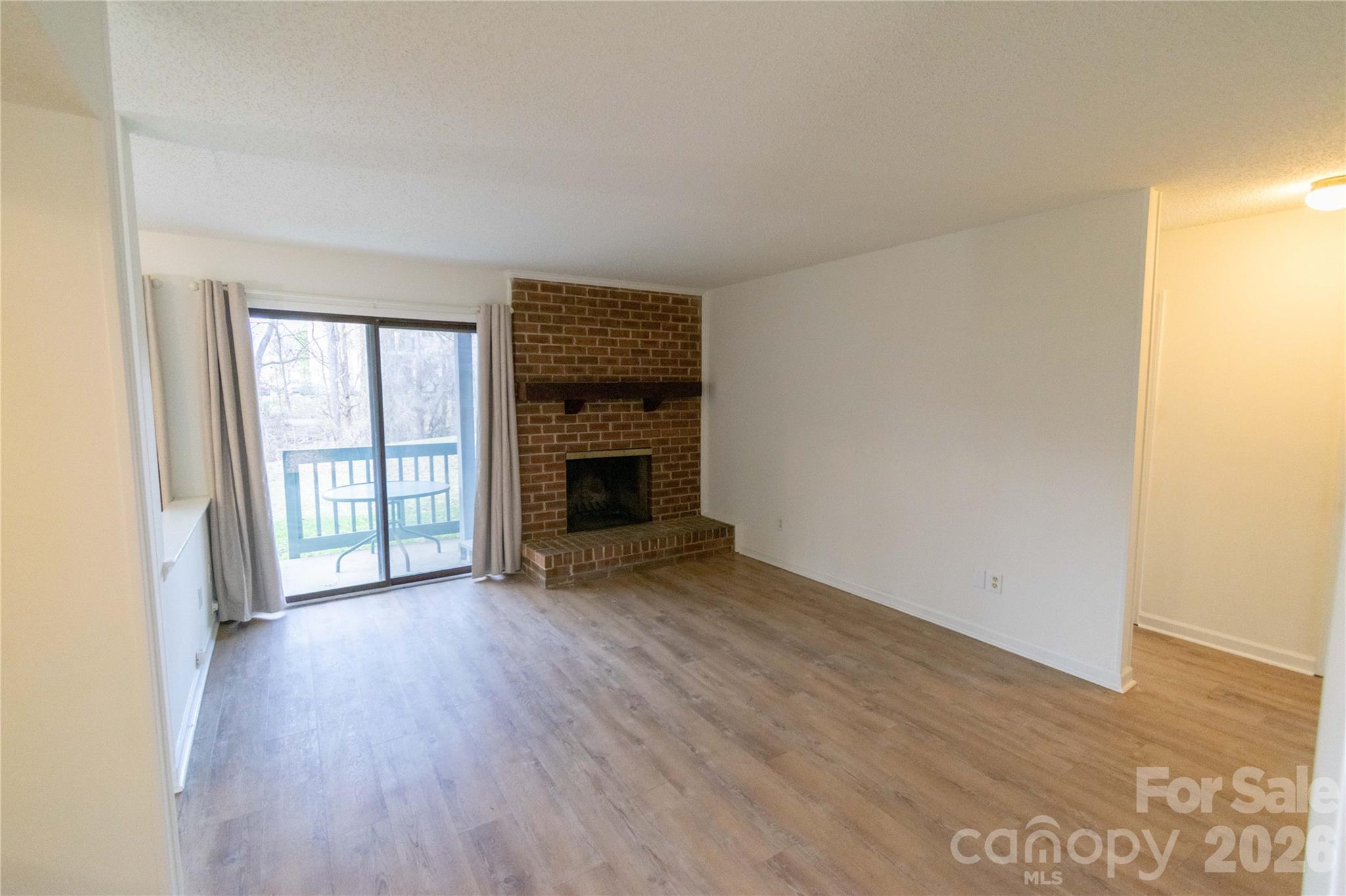 11042 Harrowfield Road Charlotte, NC 28226 - Photo 3 of 14 an empty room with wooden floor fireplace and windows