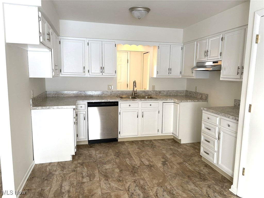 Kitchen featuring white cabinetry, stainless steel dishwasher, under cabinet range hood, and light countertops