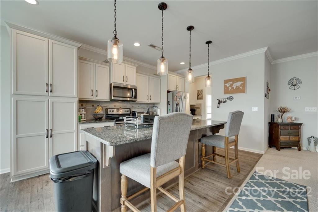 167 Old Carriage Road, Unit 226 Clover, SC 29710 - Photo 12 of 36 a kitchen with stainless steel appliances granite countertop a stove a refrigerator a kitchen island a dining table and chairs with wooden floor