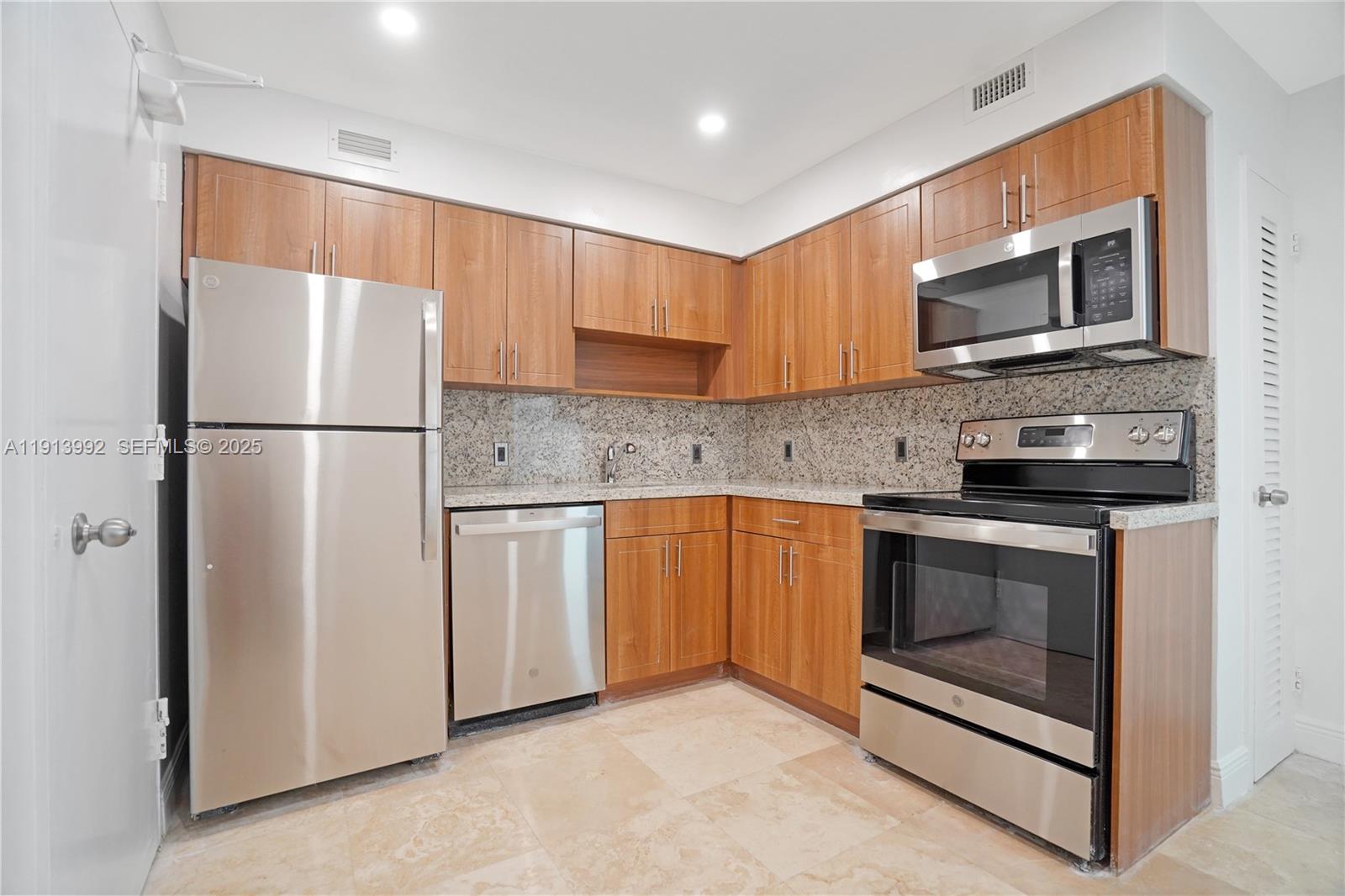 5101 Collins Avenue, Unit 14R Miami Beach, FL 33140 - Photo 3 of 9 a kitchen with stainless steel appliances granite countertop a refrigerator stove a sink and a microwave