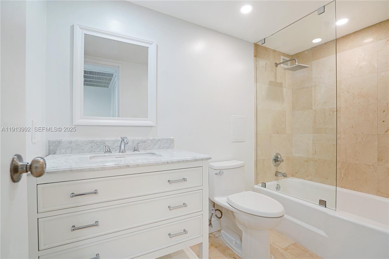 5101 Collins Avenue, Unit 14R Miami Beach, FL 33140 - Photo 6 of 9 a bathroom with a granite countertop sink toilet a mirror and shower