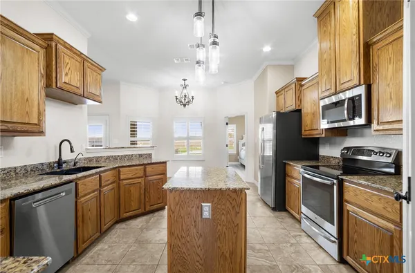 a kitchen with stainless steel appliances granite countertop a refrigerator a sink a stove and oven