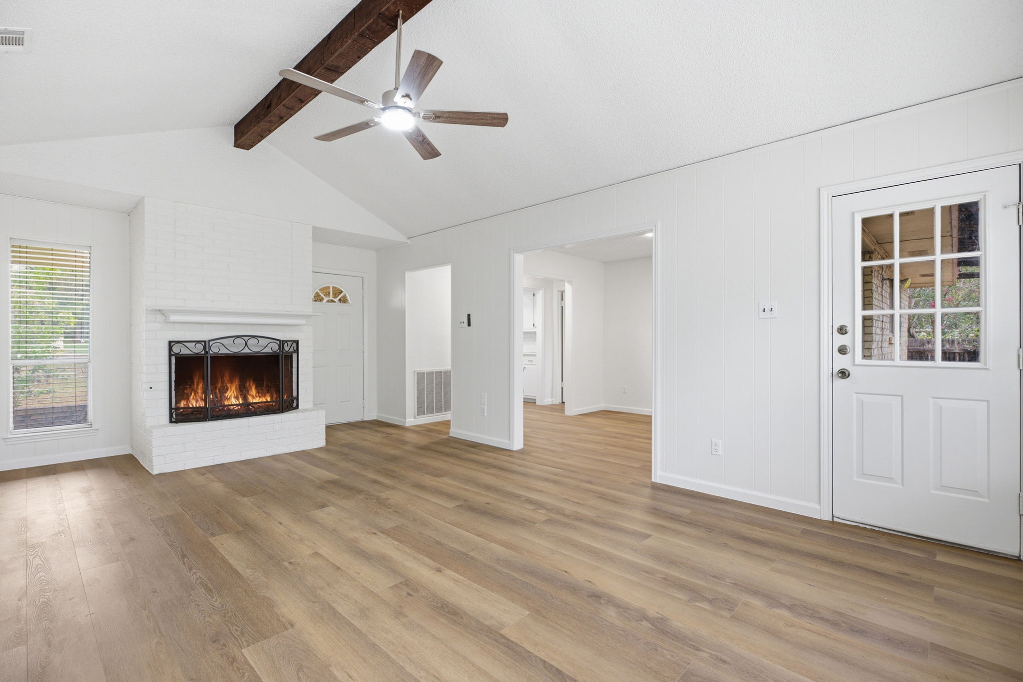 7205 Beckett Road Austin, TX 78749 - Photo 9 of 40 A well-lit living space features a cozy fireplace and attractive wood flooring, perfect for comfortable living.