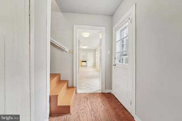 a view of a hallway with wooden floor and a bathroom