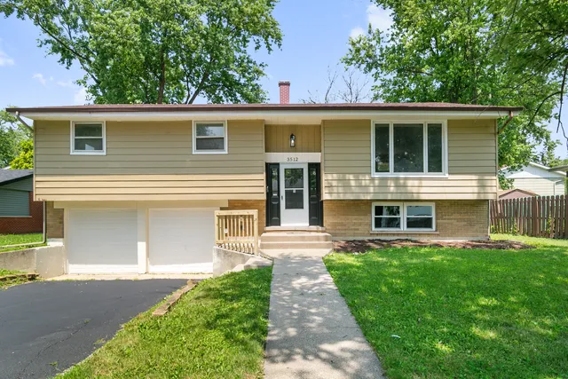 a front view of a house with a yard and large tree