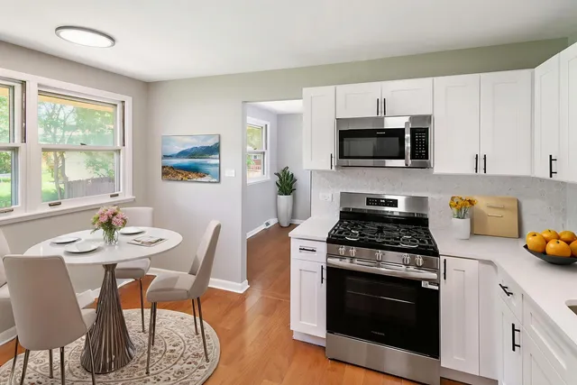 a kitchen with stainless steel appliances a stove a sink a microwave cabinets and a dining table