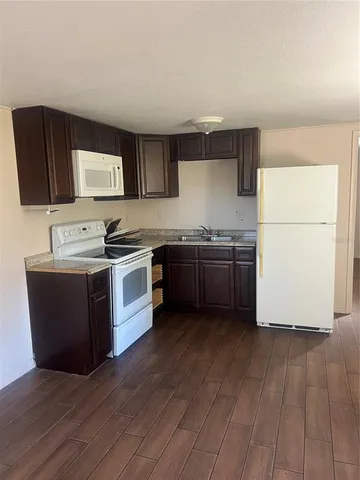 a kitchen with stainless steel appliances a sink a stove a microwave a sink a refrigerator wooden floor and cabinets