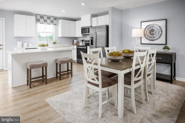 a kitchen with stainless steel appliances granite countertop a dining table chairs refrigerator and sink