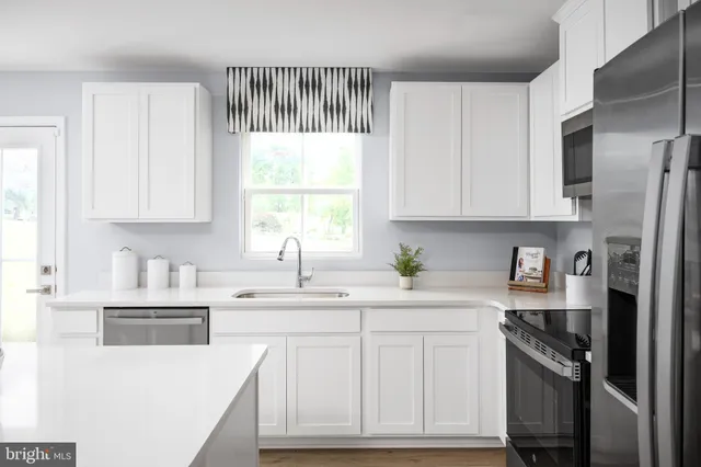 a kitchen with stainless steel appliances granite countertop a sink a stove a refrigerator and cabinets