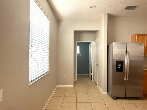 a view of a refrigerator in kitchen and an empty room with windows