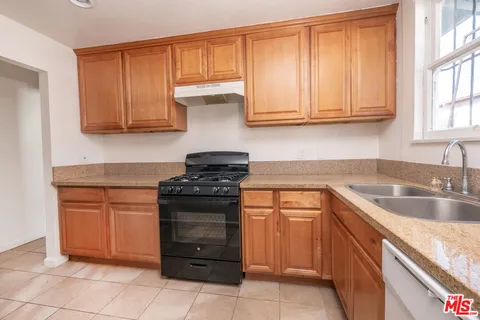 a kitchen with granite countertop a stove sink and cabinets
