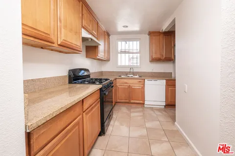 a kitchen with a sink a stove cabinets and a window