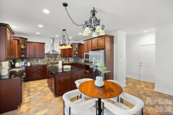 a kitchen with stainless steel appliances granite countertop a refrigerator a stove a kitchen island with chairs and wooden floor