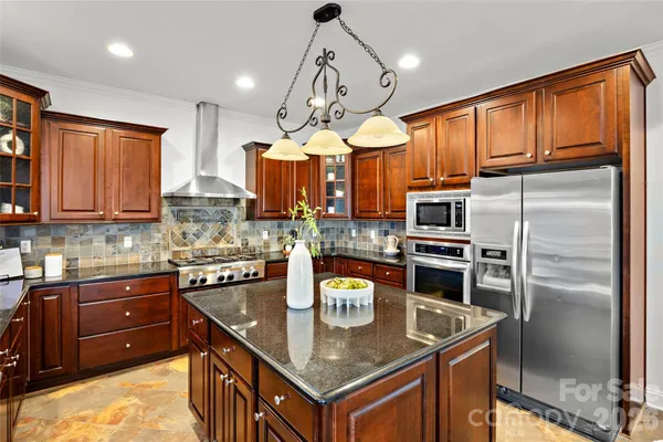 a kitchen with stainless steel appliances granite countertop a sink a stove and refrigerator