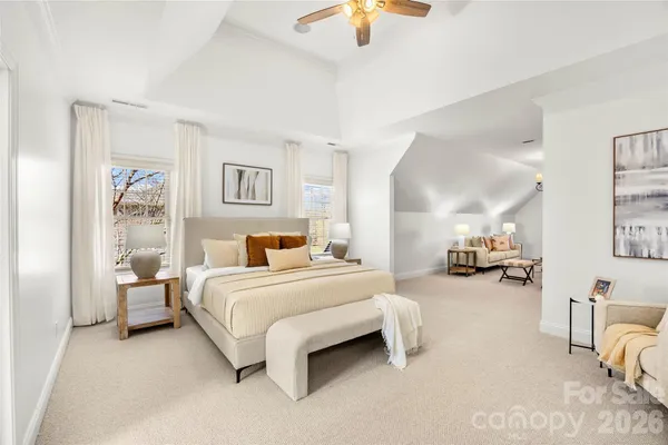 a spacious bedroom with a bed a couch and a chandelier