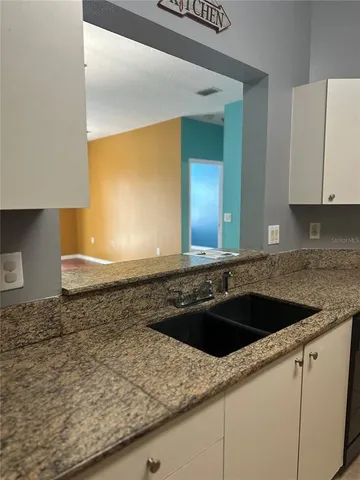a view of empty room with wooden floor and chandelier