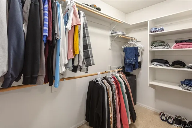 a view of walk in closet with clothes and shoes