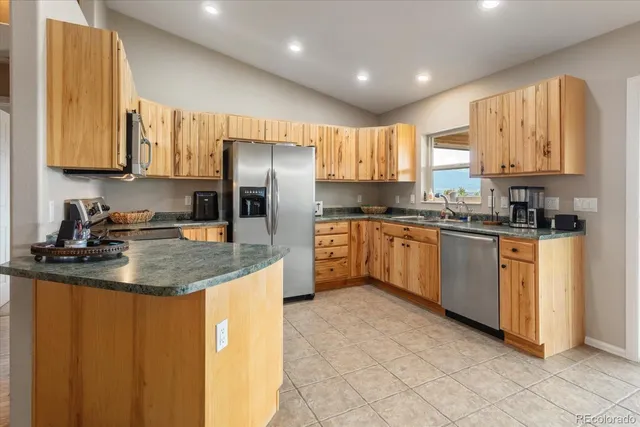 a kitchen with stainless steel appliances granite countertop a sink a stove a refrigerator cabinets and a window