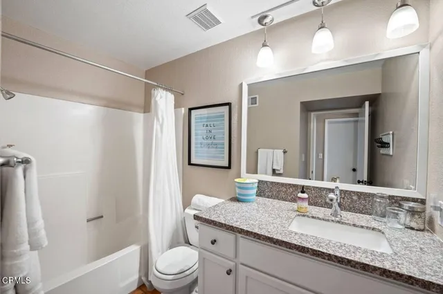 a bathroom with a granite countertop sink toilet a large mirror a vanity and shower