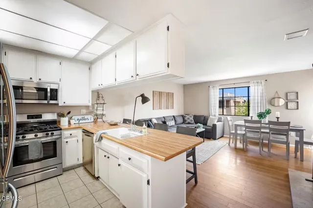 a open kitchen with stainless steel appliances granite countertop a stove top oven a sink dishwasher and white cabinets with wooden floor