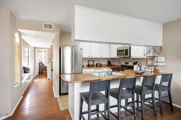a kitchen with stainless steel appliances a dining table chairs refrigerator and sink