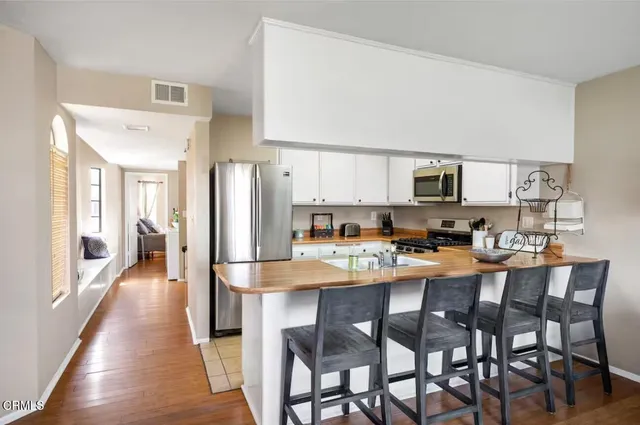 a kitchen with stainless steel appliances a dining table chairs refrigerator and sink