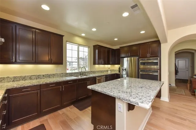 a kitchen with granite countertop center island wooden cabinets and stainless steel appliances