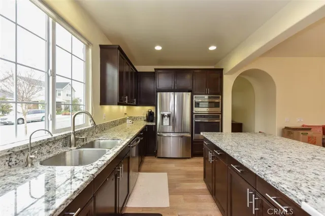 a kitchen with stainless steel appliances granite countertop a sink a stove and a refrigerator