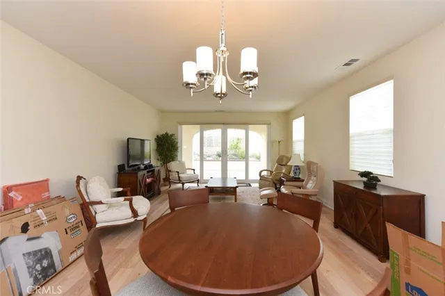 a view of a dining room with furniture a chandelier and large windows