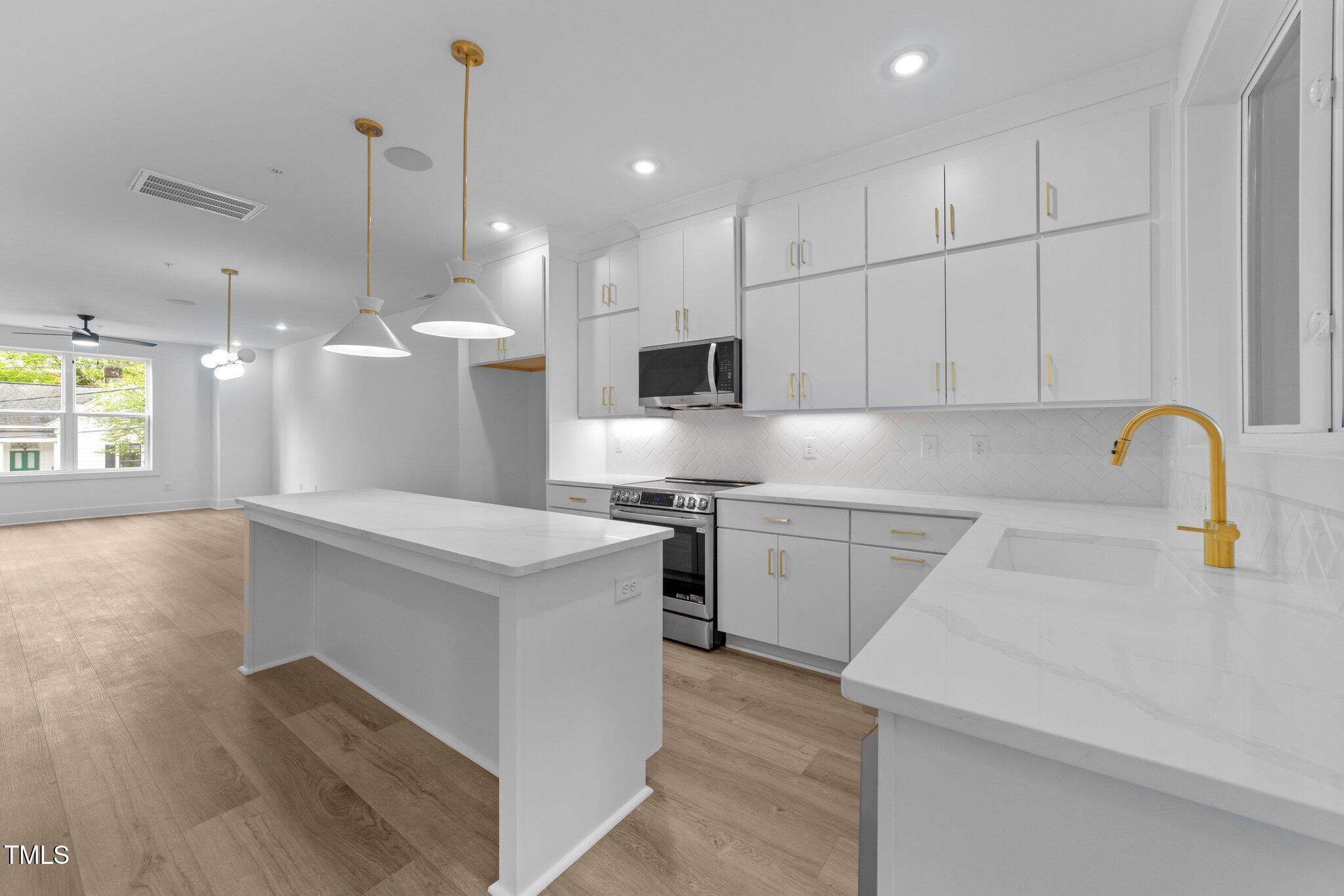 710 West North Street, Unit 102 Raleigh, NC 27603 - Photo 17 of 37 a kitchen with kitchen island white cabinets and stainless steel appliances