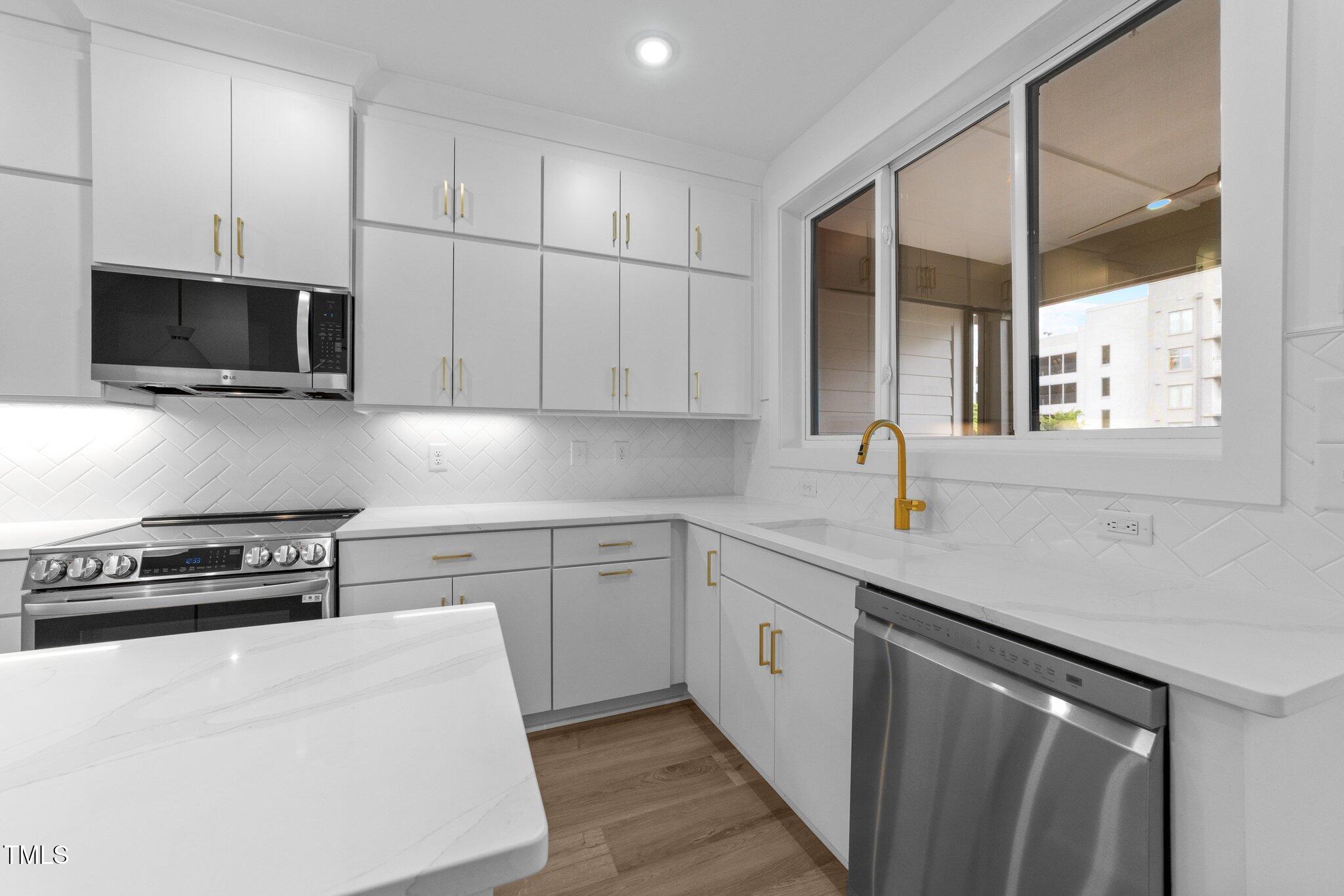 710 West North Street, Unit 102 Raleigh, NC 27603 - Photo 18 of 37 a kitchen with stainless steel appliances granite countertop a sink a stove and microwave