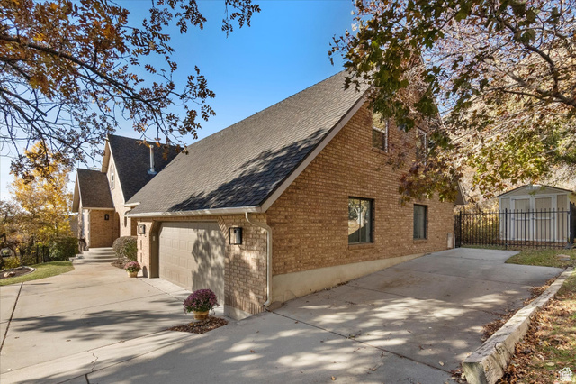 2078 Spring Oaks Drive Springville, UT 84663 - Photo 5 of 40 View of home's exterior with brick siding, a shingled roof, driveway, and a storage unit