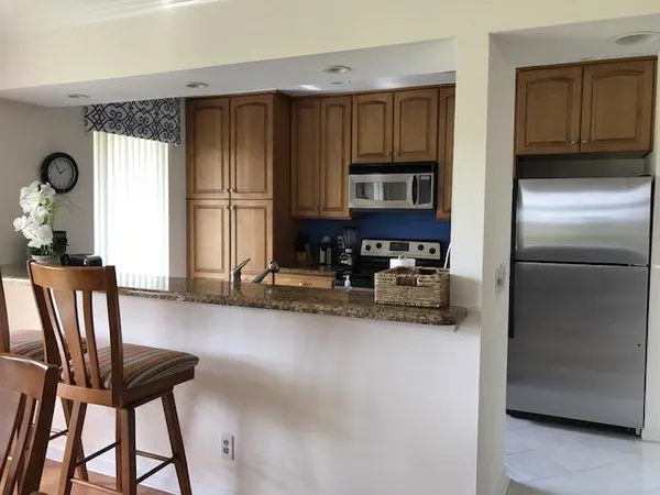 a kitchen with stainless steel appliances granite countertop a refrigerator a stove a sink a dining table and chairs with wooden floor