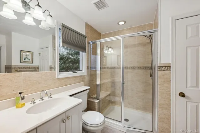 a bathroom with a shower sink vanity mirror and toilet