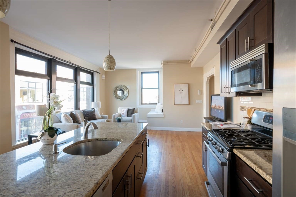 191 Main Street, Unit 2A Gloucester, MA 01930 - Photo 12 of 15 a kitchen with granite countertop a sink and a stove top oven