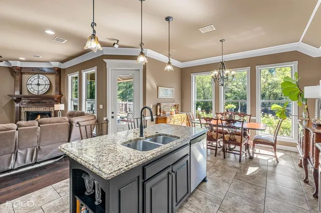 a kitchen with granite countertop a stove a sink a dining table and chairs with wooden floor