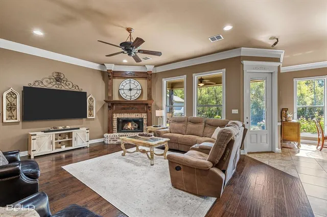 a living room with furniture a fireplace a flat screen tv and wooden floor